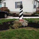 A model lighthouse stands in the middle of a newly mulched yard