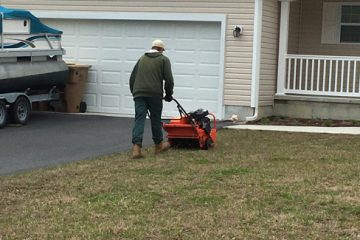 A person pushing a mower in front of a house