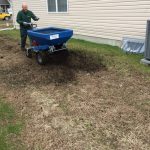 A blue cart spreading fertilizer over an area