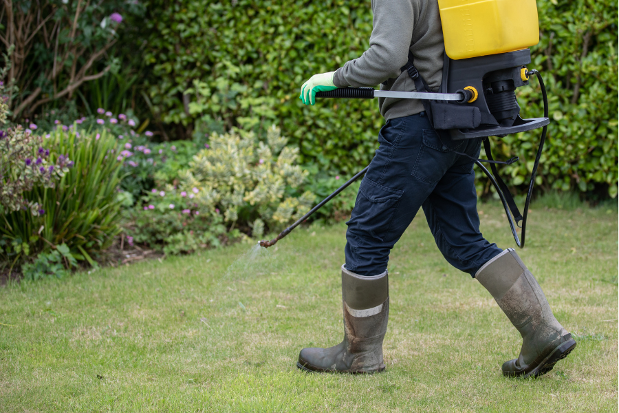 Person in boots with a weed sprayer backpack